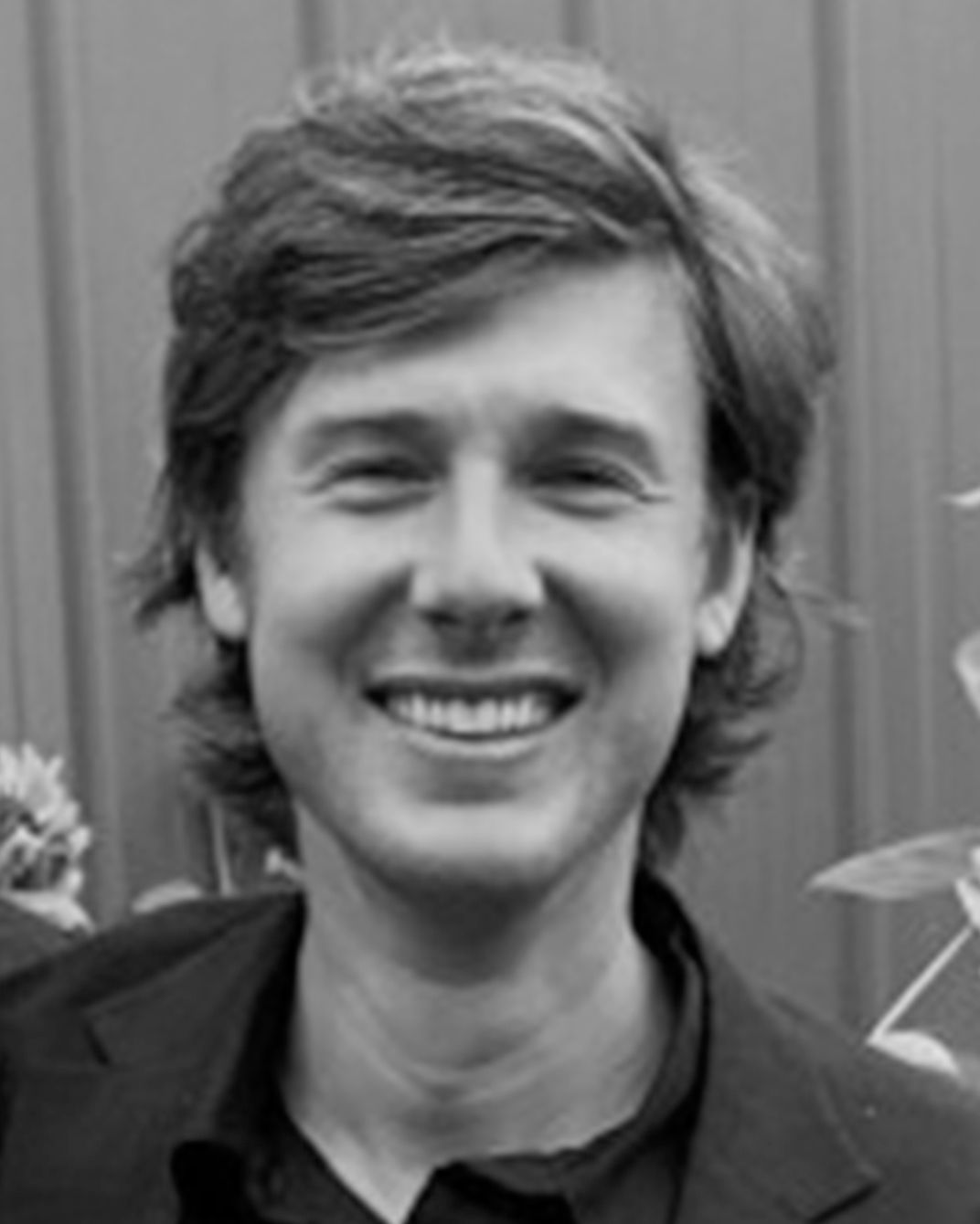 Smiling person in a black shirt, posing against a plain background.