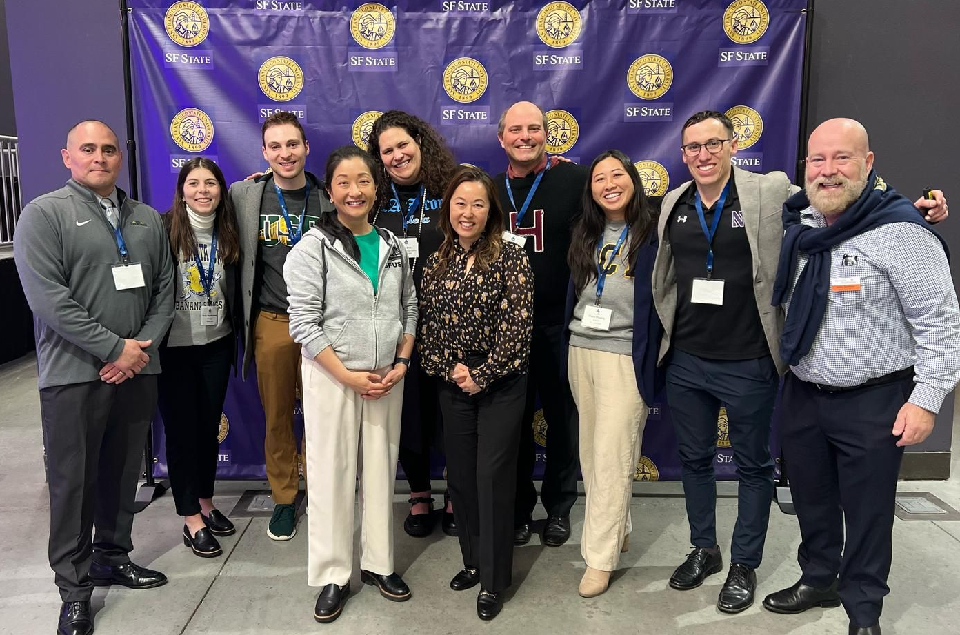 Group of smiling professionals posing in front of a purple Rotary International backdrop at a conference