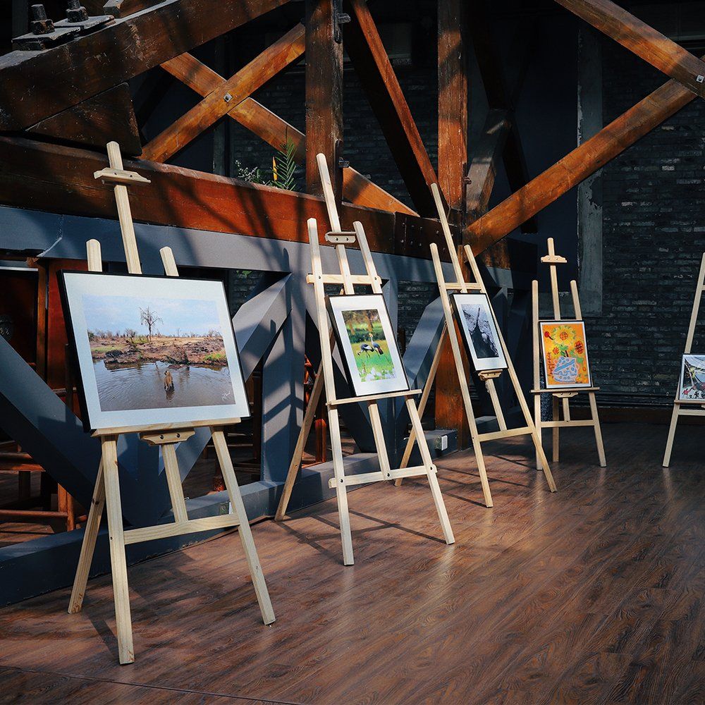 Art gallery with five paintings displayed on easels in a rustic wooden interior