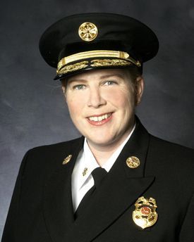 Uniformed officer smiling in formal portrait against a dark background