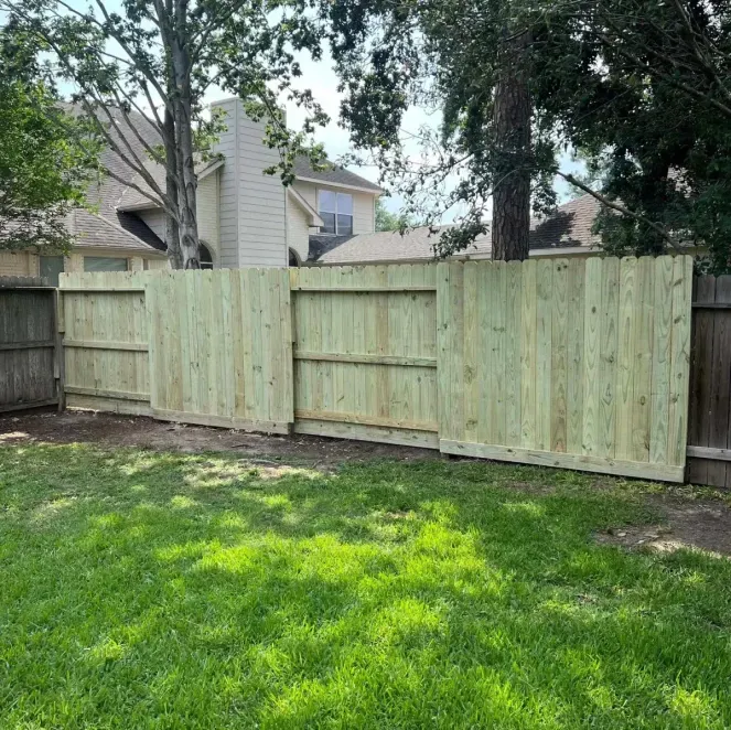 Wooden backyard privacy fence with grass and trees in a suburban yard