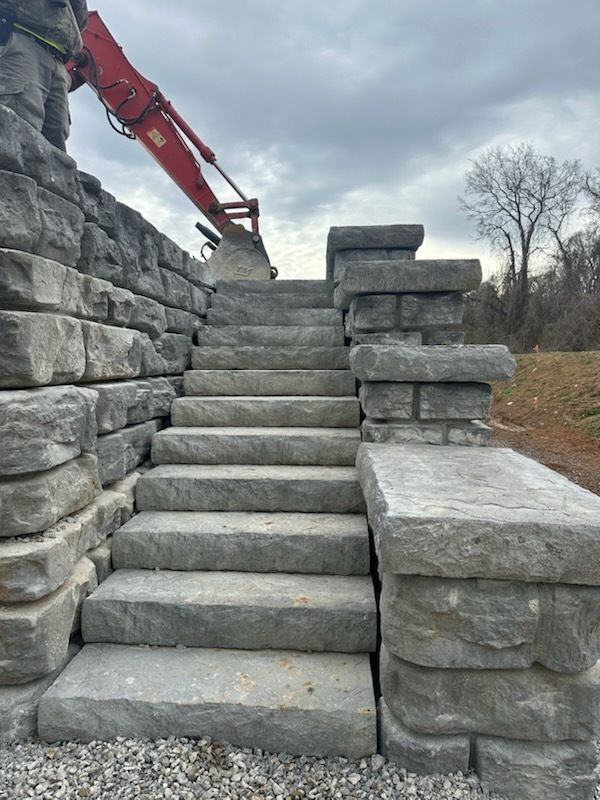Stone steps and retaining wall under construction with red machinery.