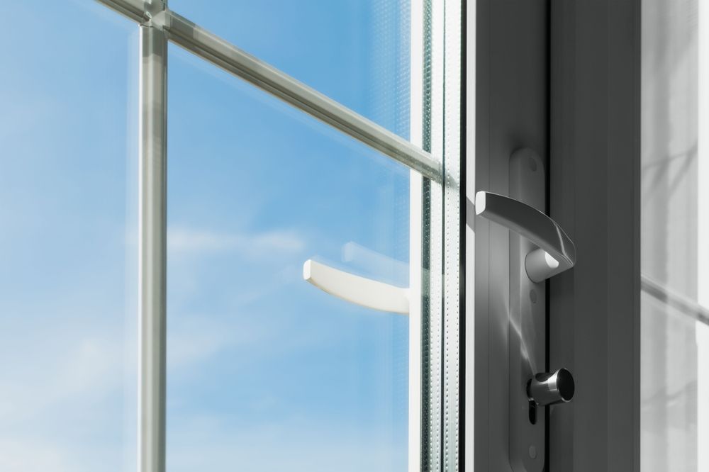 White window with a handle, open against a bright blue sky with clouds.