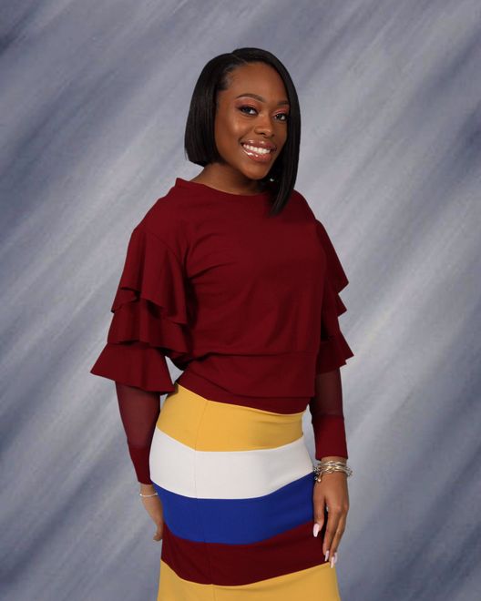 A woman is wearing a red sweater and a striped skirt.
