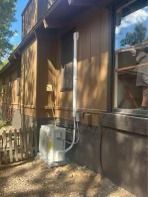 Gas meter and vent pipe attached to a brown house exterior, next to a window.