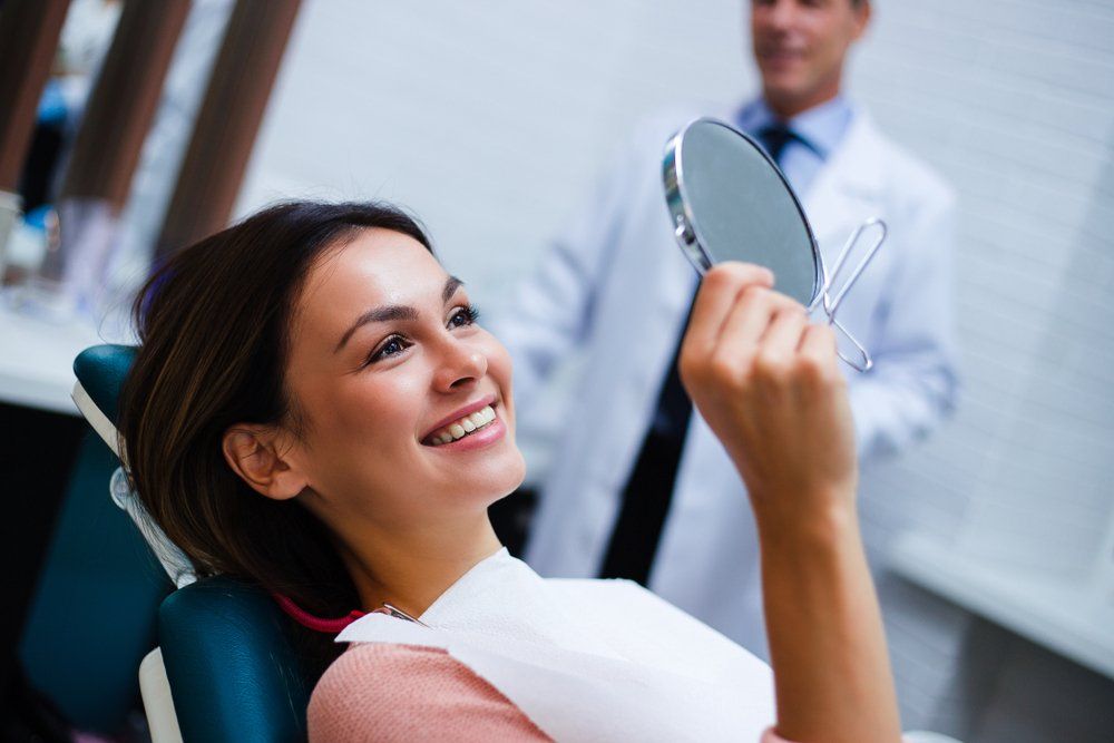 Lady Holding Mirror — Ballina Denture Clinic Michael J Parker in Ballina, NSW