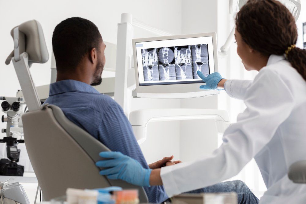 A Dentist is Looking at an X-ray of a Patient's Teeth — Ballina Denture Clinic Michael J Parker in Ballina, NSW