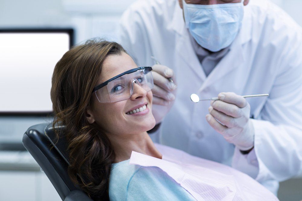 A Woman Sitting on Dental Chair While Dentist Examines — Ballina Denture Clinic Michael J Parker in Alstonville, NSW