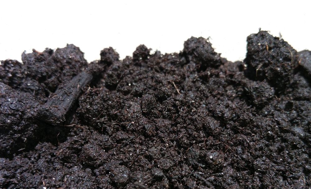 A Person Wearing Green Gloves is Holding a Pile of Mulch — Wodonga Sand & Soil in Wodonga, VIC