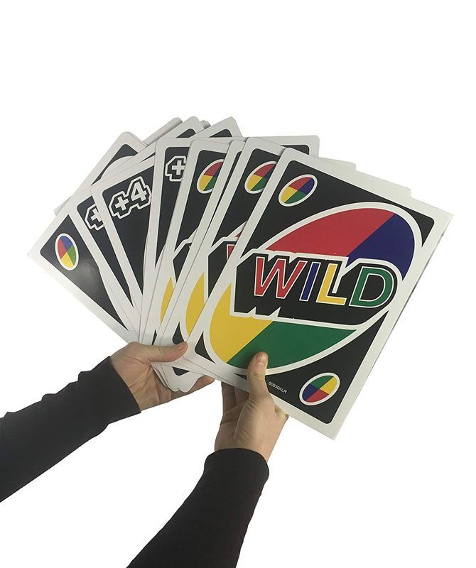 Hands hold a fan of Uno cards, highlighting multiple black 