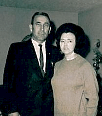 Two people standing indoors, dressed formally