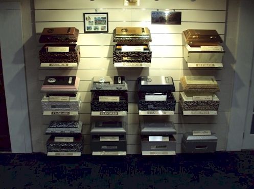 Wall display of stacked vintage paper/cardboard boxes in a shop or exhibit, with small labels and photos above.