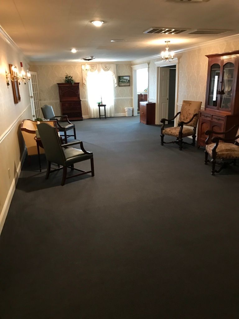 Long hallway with carpet, chairs, cabinets, and ceiling lights in a building lobby