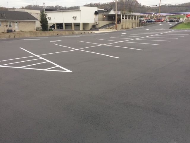 Empty parking lot with white painted lines beside low buildings on an overcast day