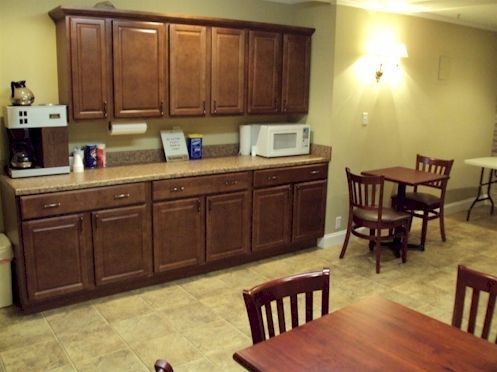 Cozy lobby with tiled floor, chairs, round table, lamp, and a small kitchenette area.