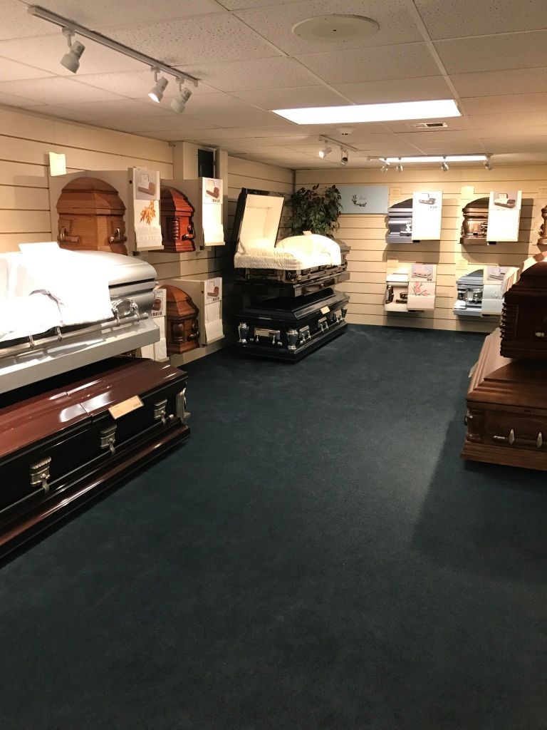 Funeral showroom with several dark wooden caskets displayed under ceiling lights.