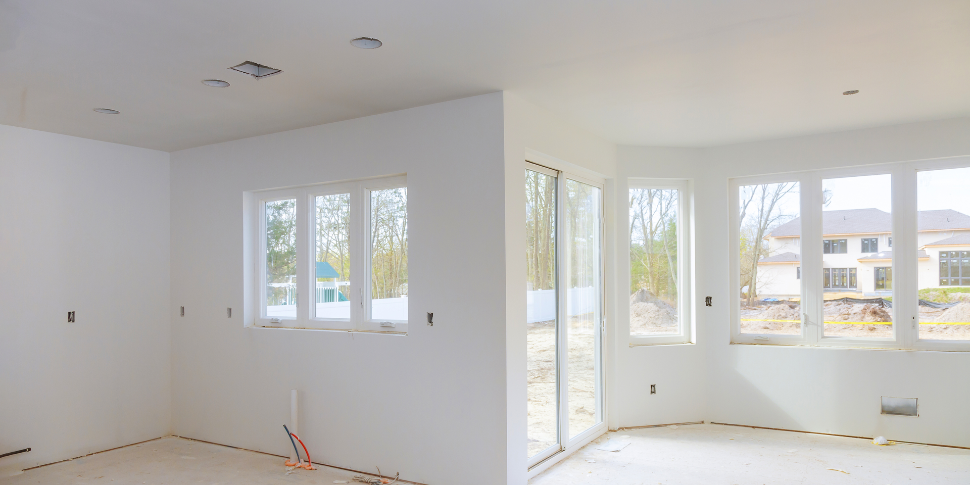 Two empty rooms, freshly painted white. One room has a window, the other, large glass doors. Both have unfinished floors.