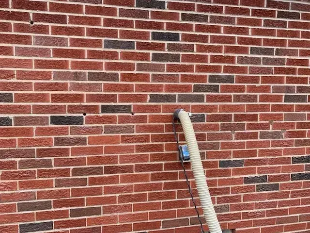 A brick wall with a hose attached to it.