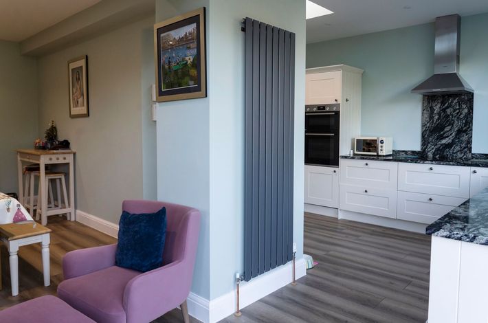 A kitchen with green cabinets and white counter tops in a Large-Scale Retrofitting in East Sussex