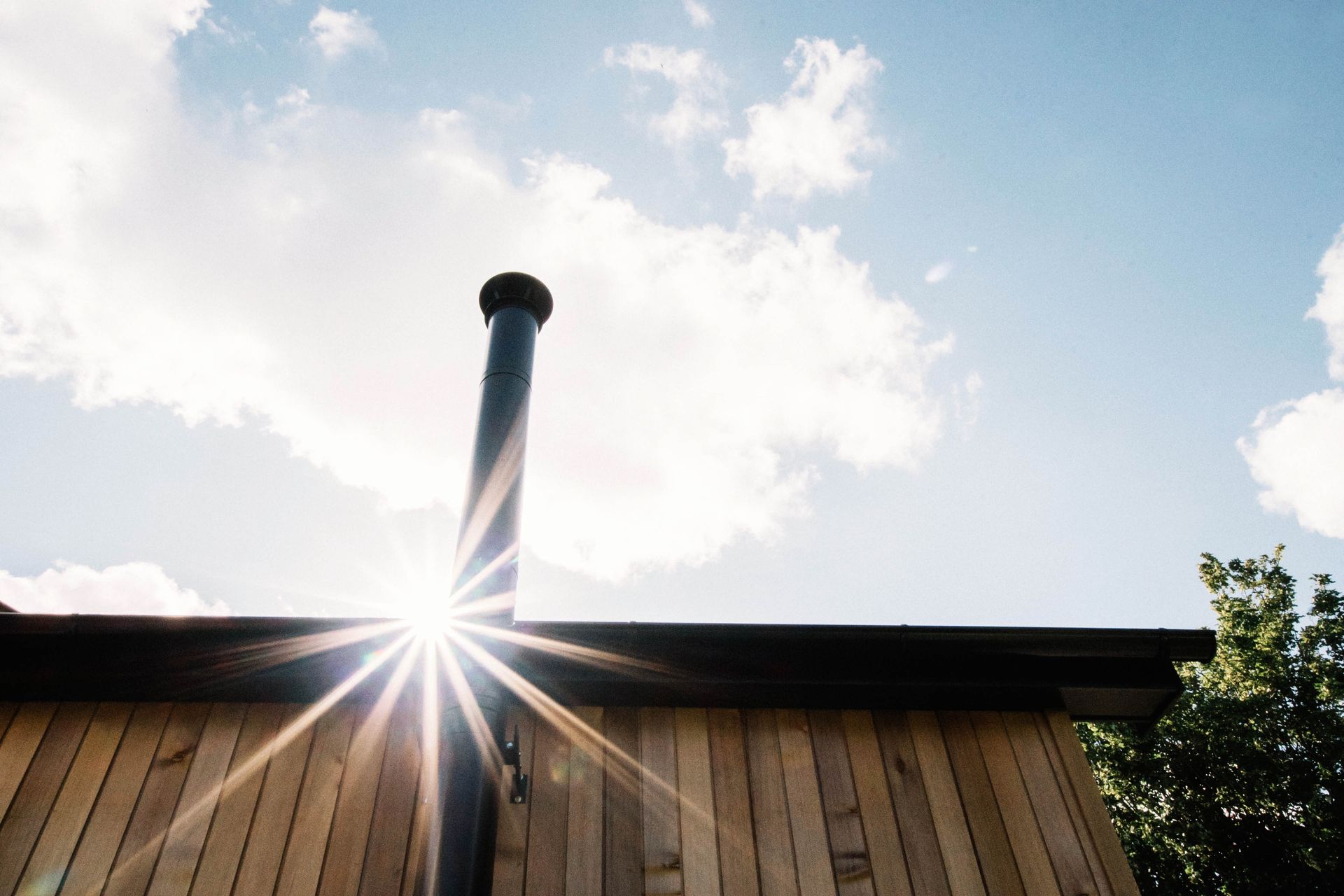 A small wooden building with a black roof is in a backyard in a Passivhaus New Builds in East Sussex