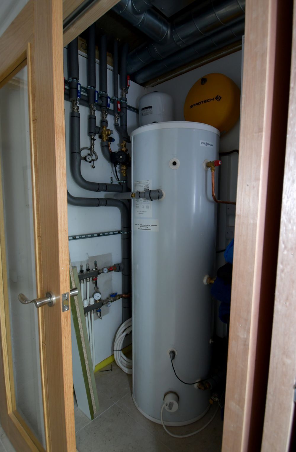A water heater is sitting in a closet next to a door  in a Large-Scale Retrofitting in East Sussex