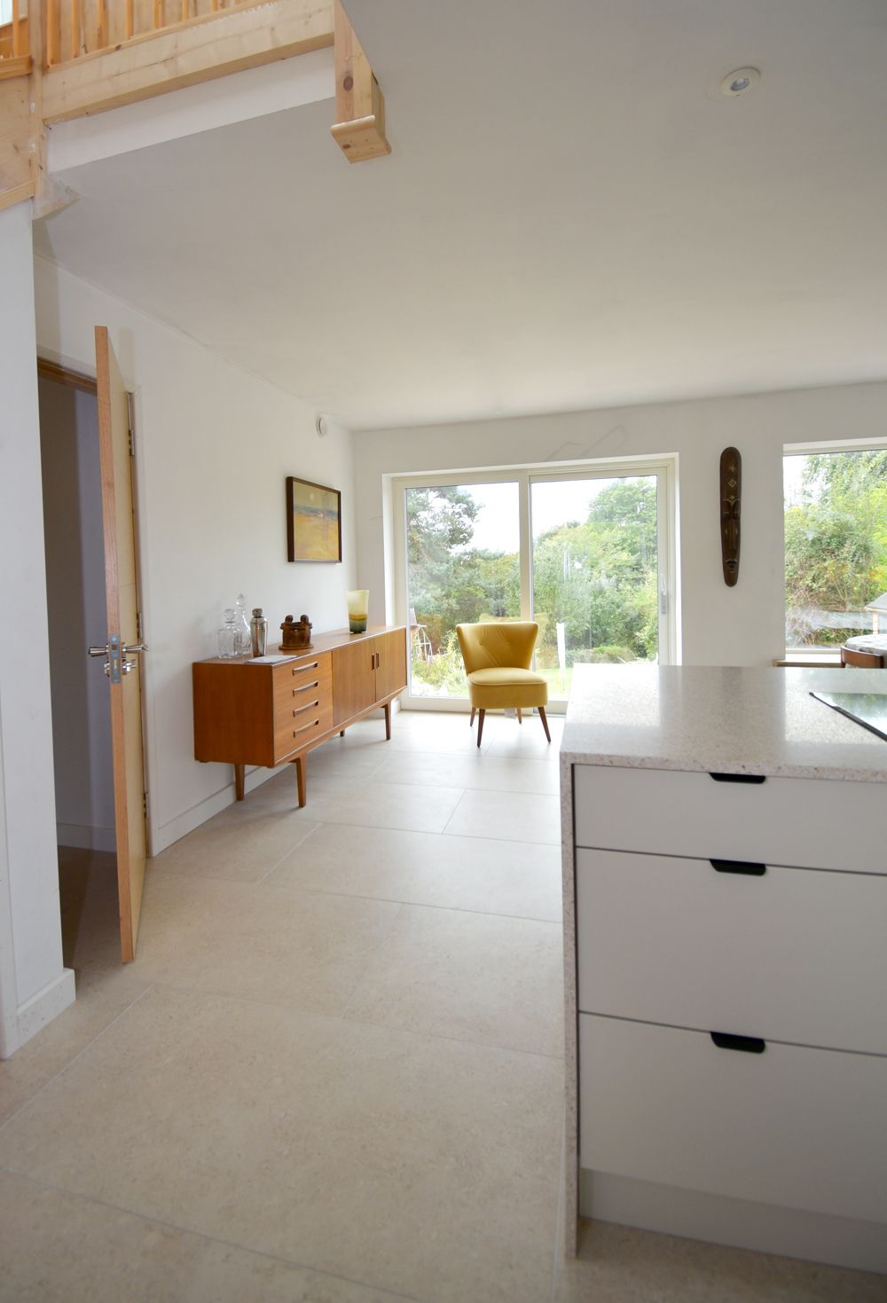 A kitchen with white cabinets and a yellow chair  in a Retrofit Consultancy in East Sussex