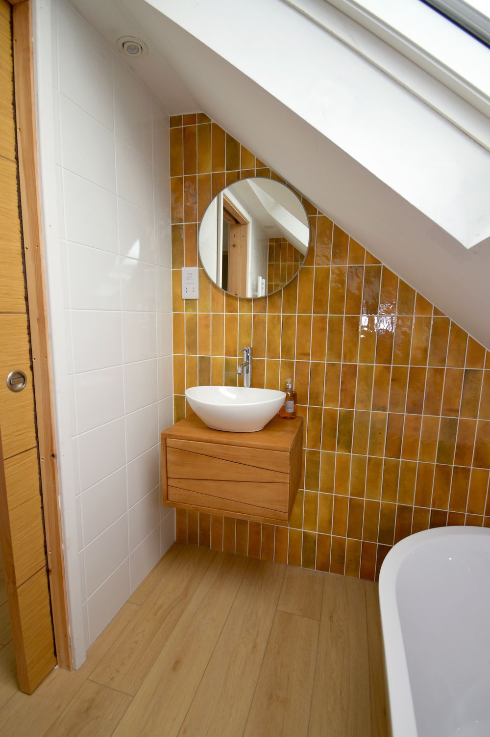 A bathroom with a sink , mirror and bathtub  in a Large-Scale Retrofitting in East Sussex
