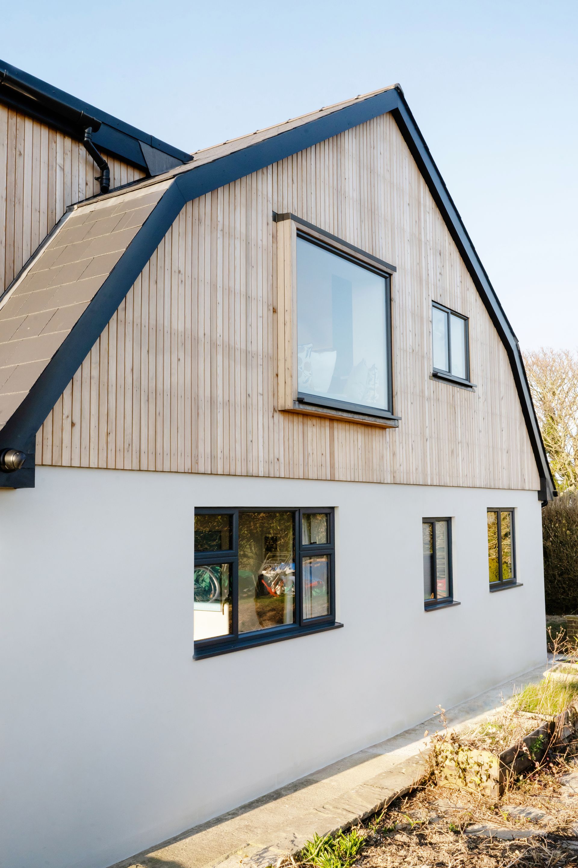 A house with a lot of windows and a brick roof in a Passivhaus New Builds in East Sussex