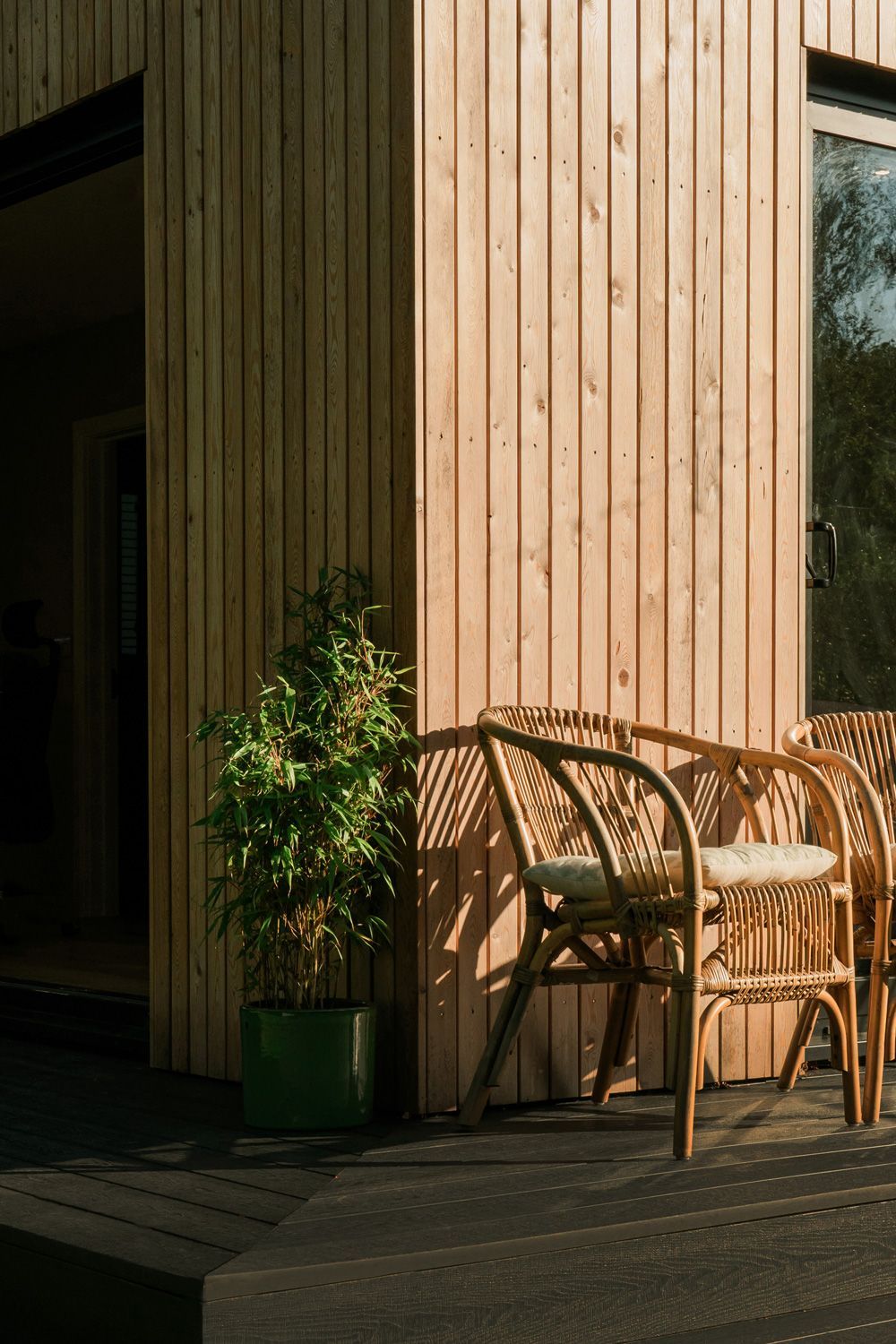 Two wicker chairs are sitting on a wooden deck in front of a wooden building in a Passivhaus New Builds in East Sussex