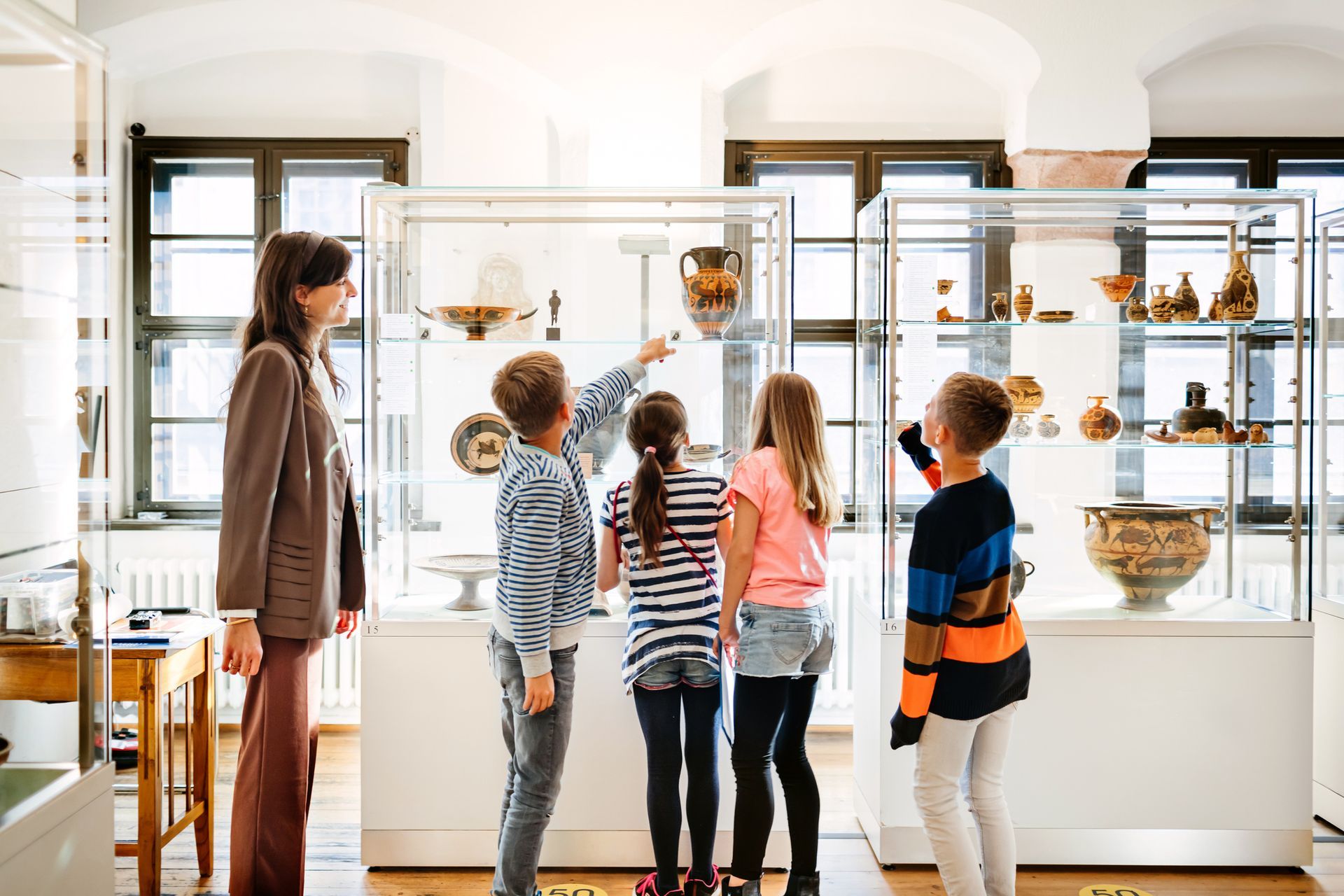 A group of children are looking at a display case in a museum. A group of children are looking at a display case in a museum.