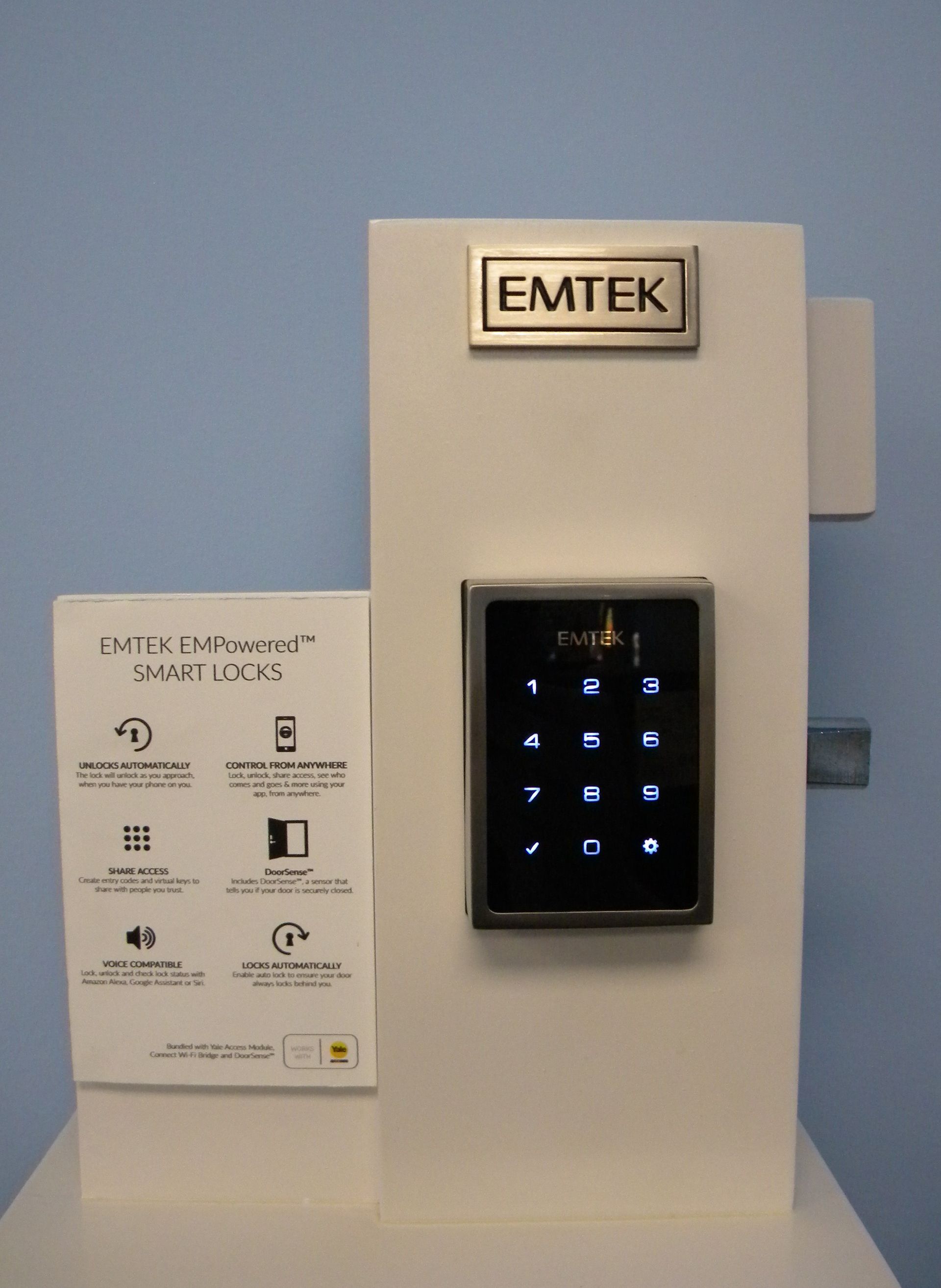 Emtek EMPowered smart lock display featuring a touchscreen keypad and informational panel about remote access, automatic locking, and voice control features.