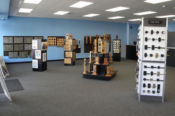Showroom in Charm's Locksmith shop featuring multiple display stands with door hardware, including handle sets, knobs, locks, and keypad models arranged throughout the space.