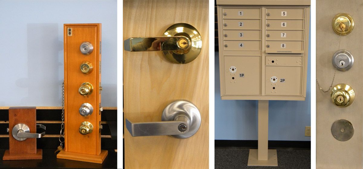 Display of various door knobs, lever handles, deadbolts, and a multi-unit mailbox cabinet, shown on wooden mounts and a freestanding mailbox pedestal.