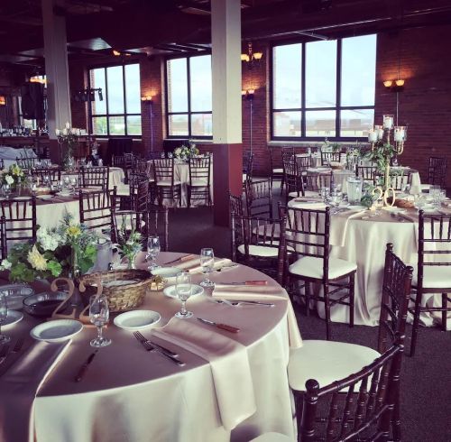 Elegant banquet hall with round tables, floral centerpieces, and dark chairs.