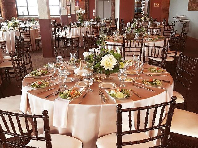 Elegant banquet hall set for a wedding with round tables, flowers, and place settings.