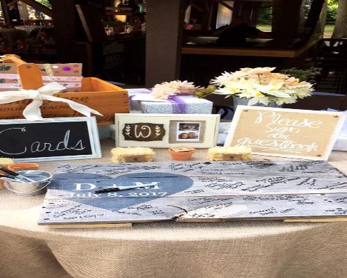 Wedding guest book table with gifts and signs; burlap cloth, wooden crates, and chalkboards.