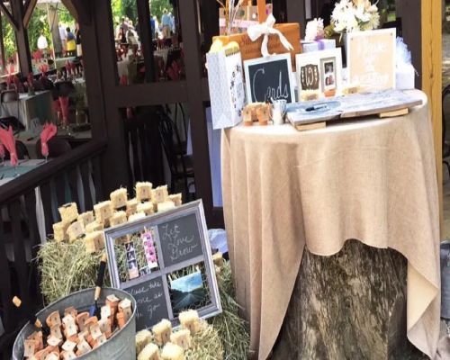 Wedding reception table with burlap cloth, guest book, framed photos, soaps, and gifts.