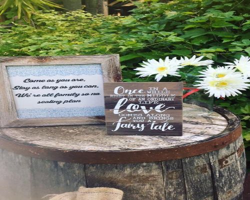 Two signs on a barrel with flowers. One says 