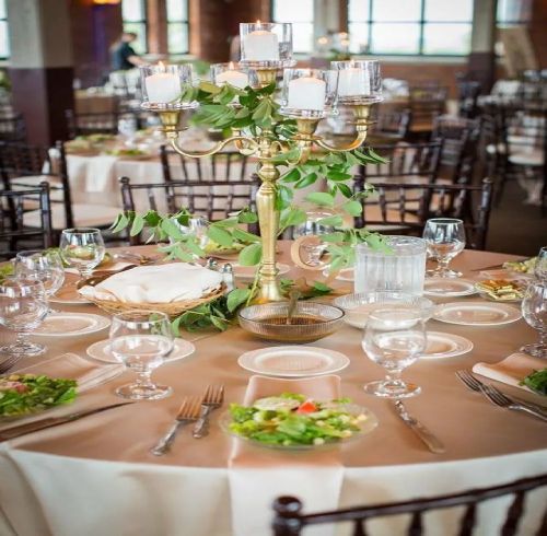 Elegant wedding reception table set with candelabra, greenery, and place settings.