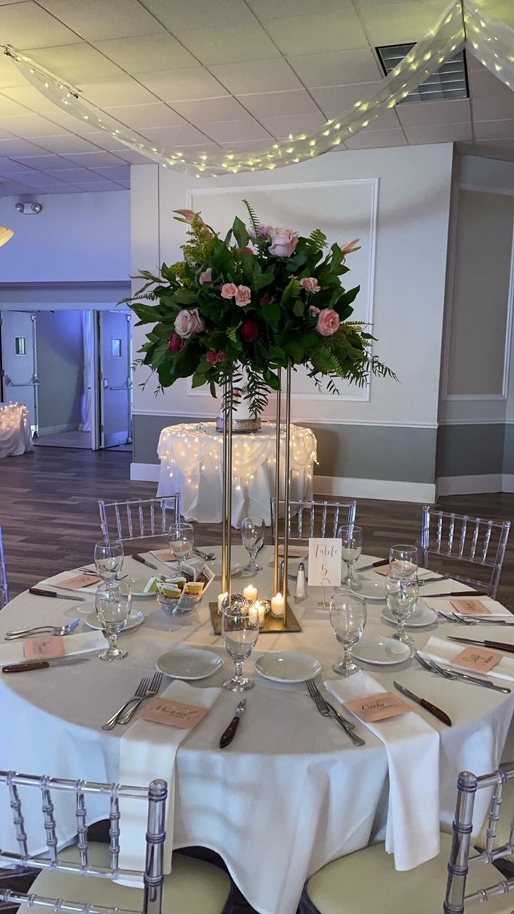 Elegant round table setting with tall floral arrangement centerpiece.