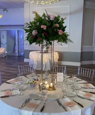 Wedding reception table set with floral centerpiece, candles, and clear chairs.