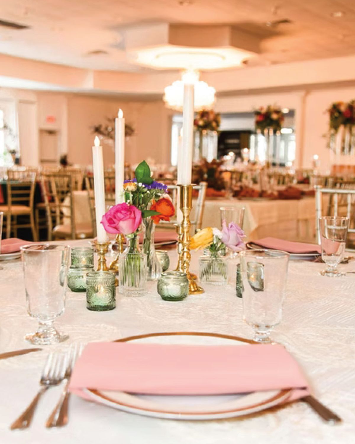 Elegant wedding reception table setting with pink accents and flower centerpieces.