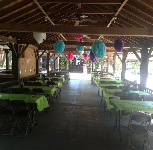 Pavilion with green tablecloths, decorated with colorful paper balls, and tables ready for a celebration.