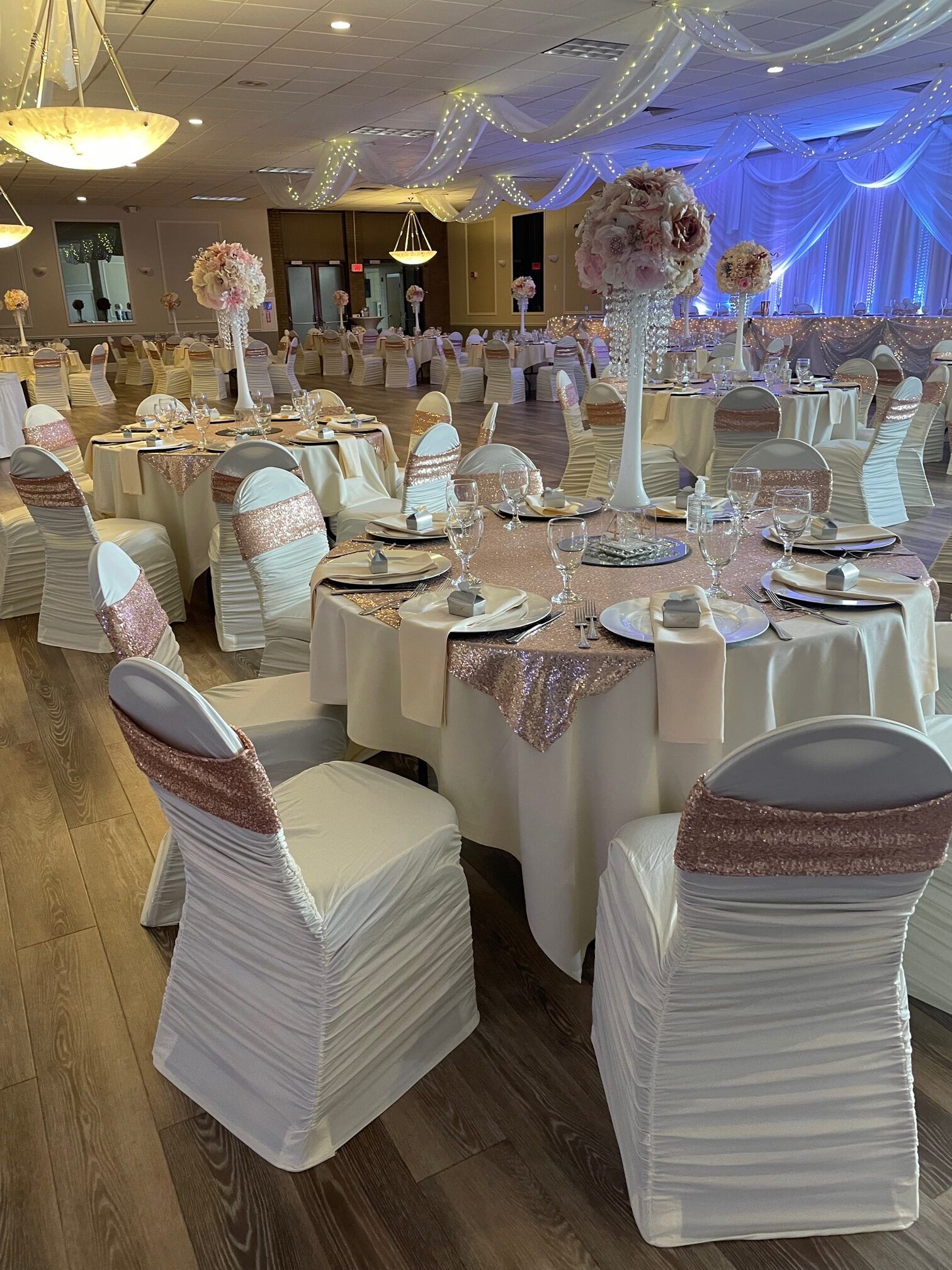 Elegant banquet hall decorated in cream and rose gold, set for a formal event.