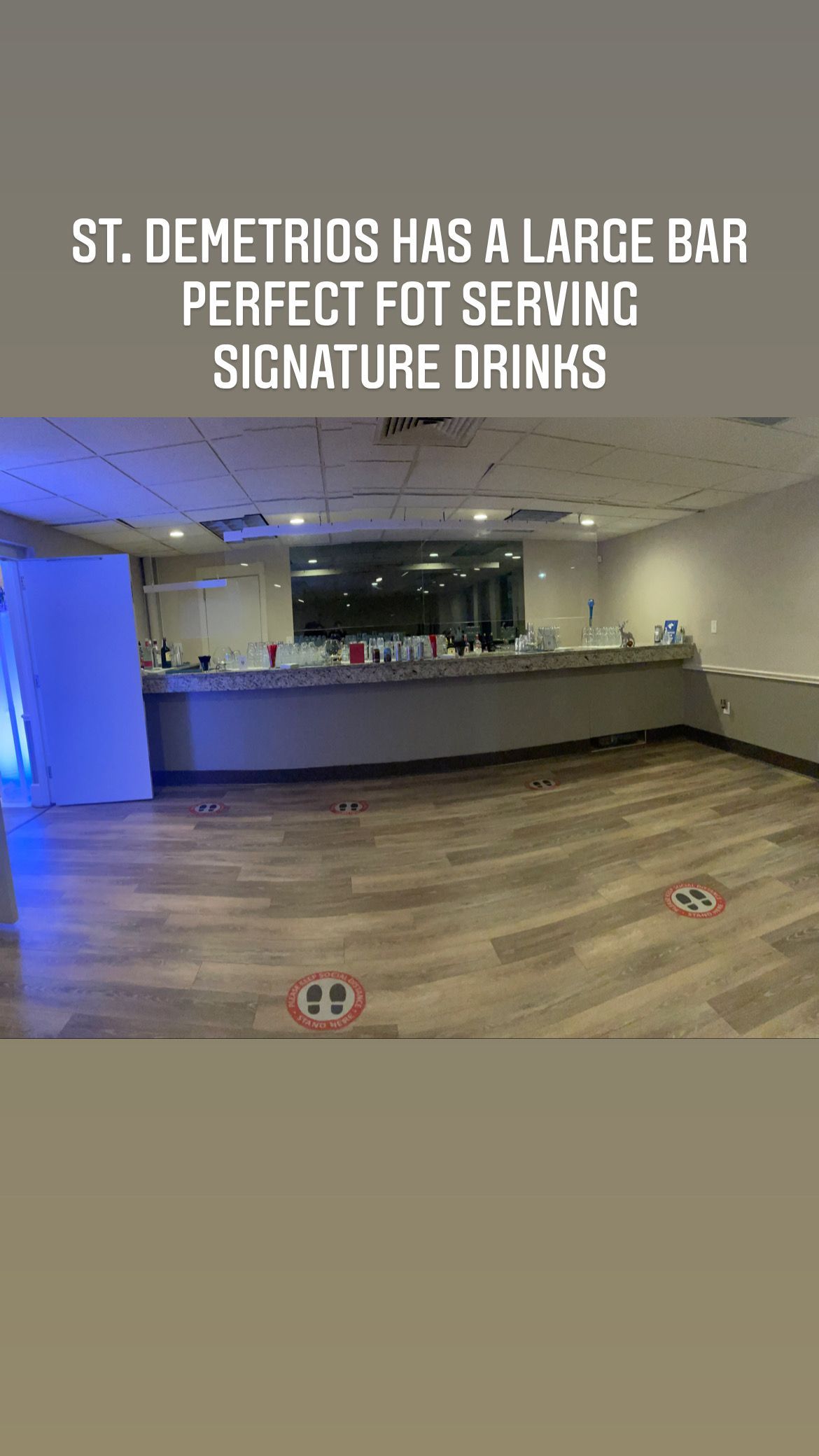 Empty event space with a large bar, ready for signature drinks. Wooden floor, walls, and lighting.