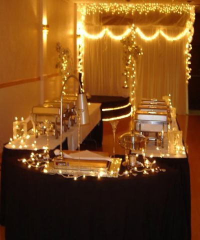 Buffet table decorated with lights, offering food in a softly lit event space.