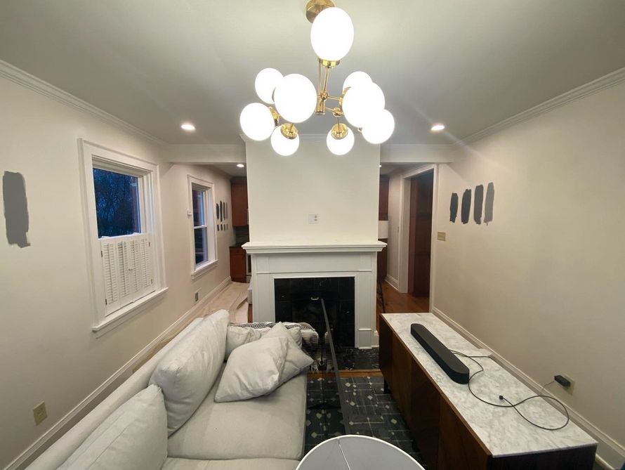 Bright living room with white sofa, fireplace, chandelier, and marble coffee table