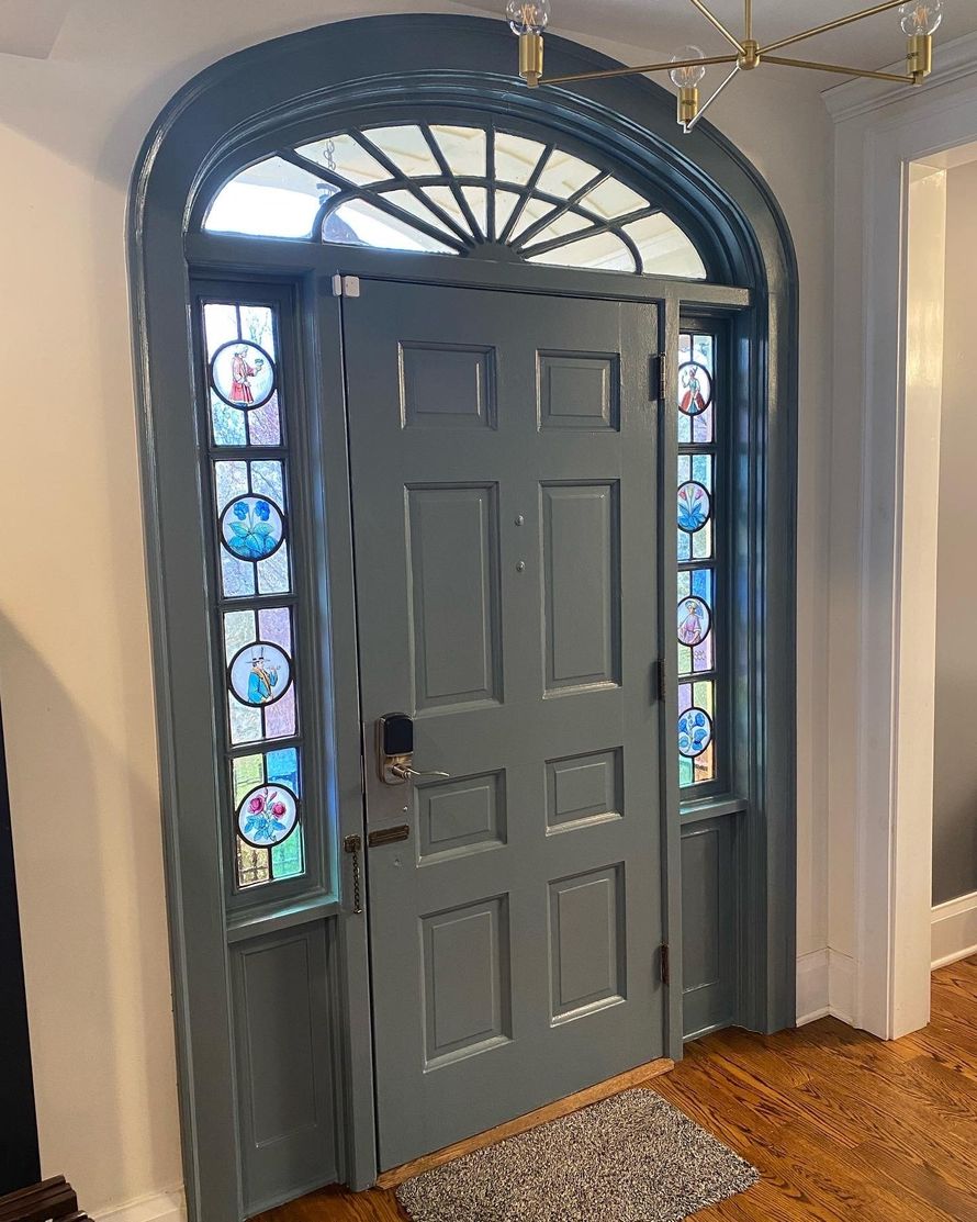 Gray front door with arched stained-glass sidelights and transom in an entryway