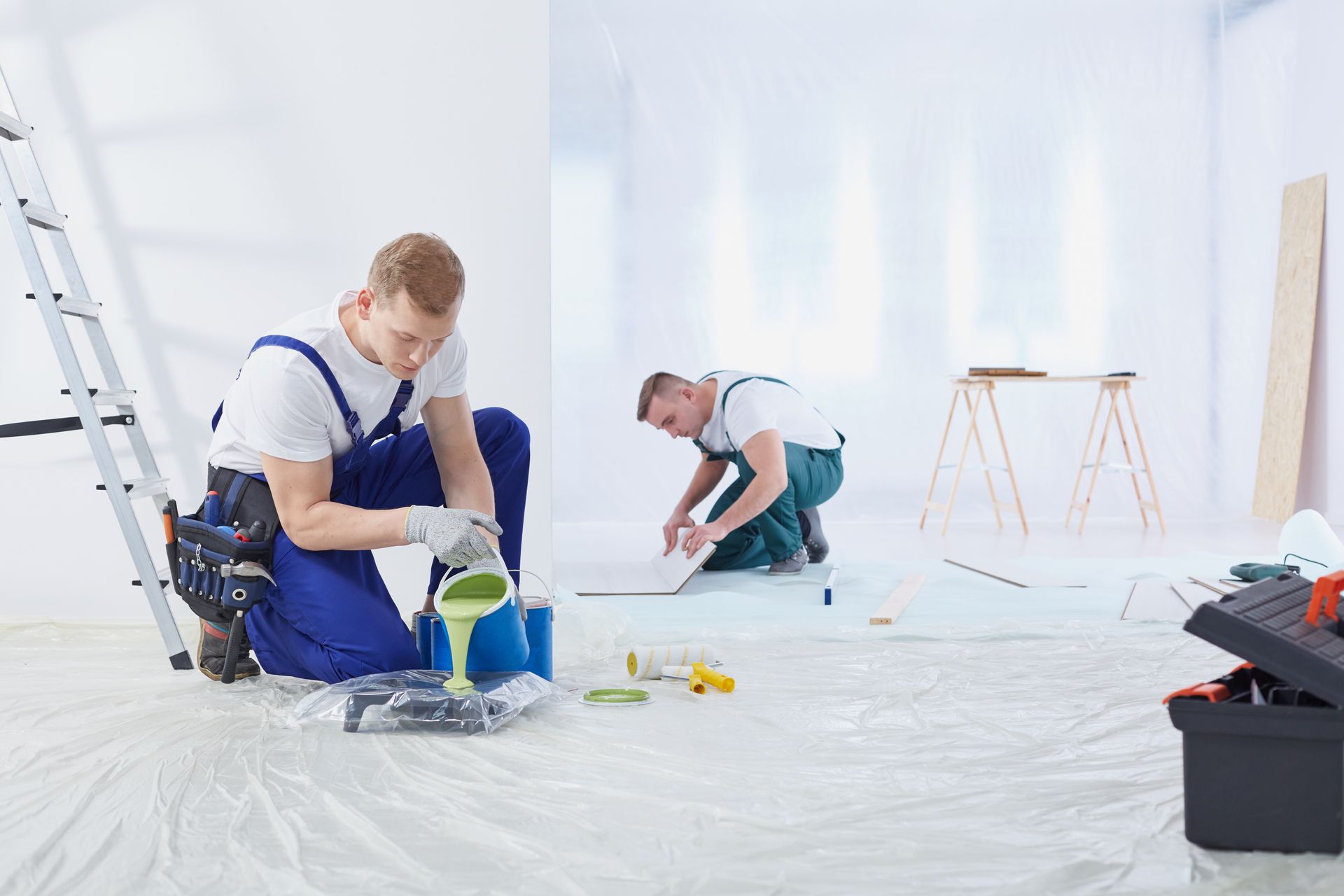 Painters preparing a bright residential room for renovation with paint supplies and tools. Painters preparing a bright residential room for renovation with paint supplies and tools.