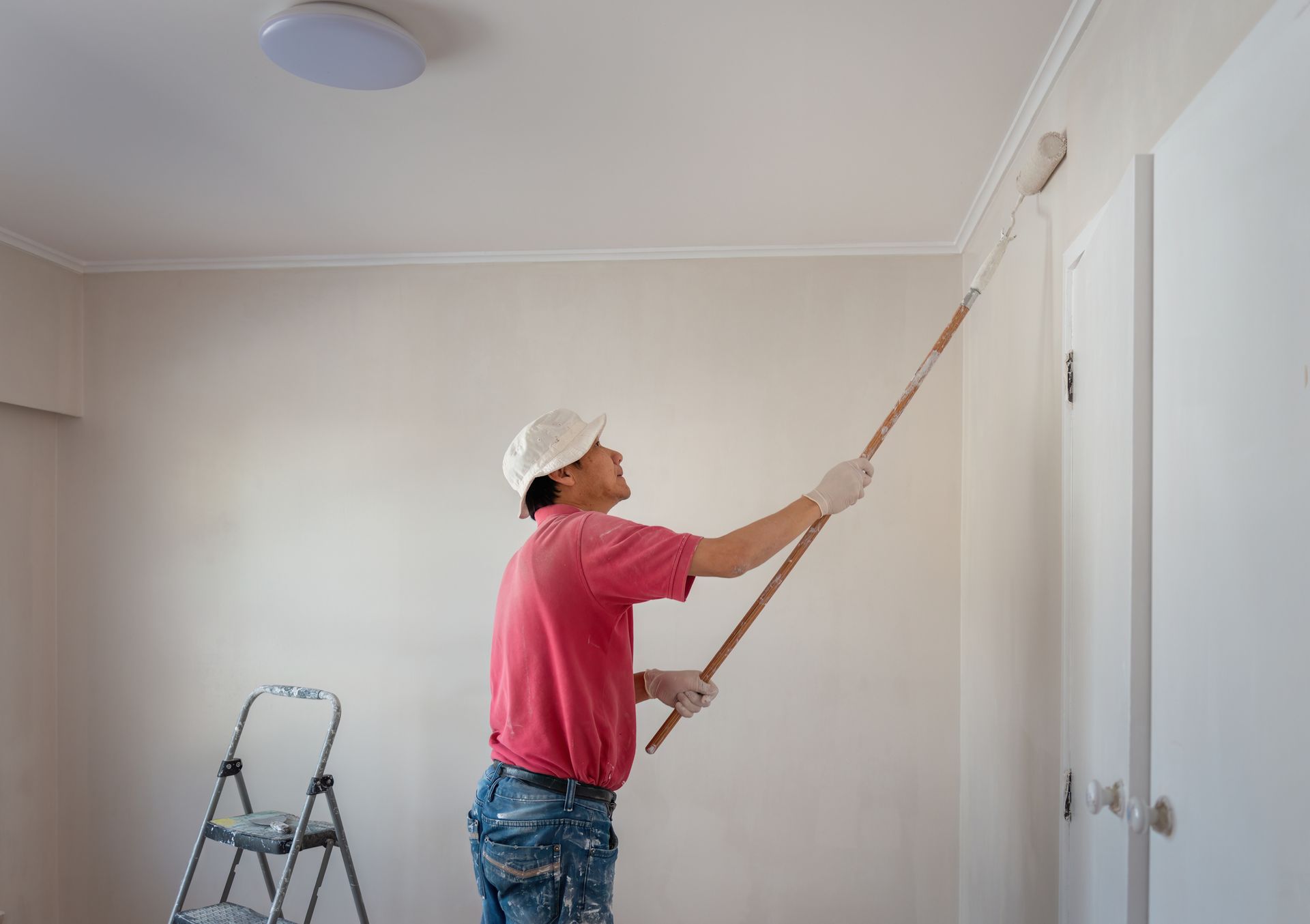 A man is painting a wall with a roller in a home renovation project.